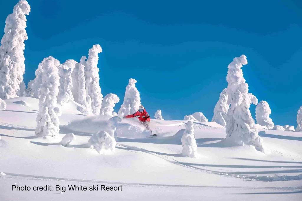 snowboarder in deep powder on a sunnyd at Big White Ski Resort