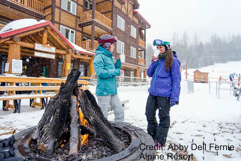 two women enjoying a coffee around a bonfire at Fernie Ski Resort