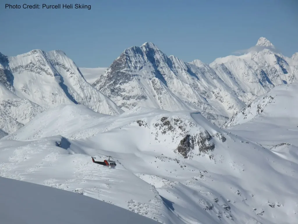 helicopter flying over snowy peaks near Kicking Horse