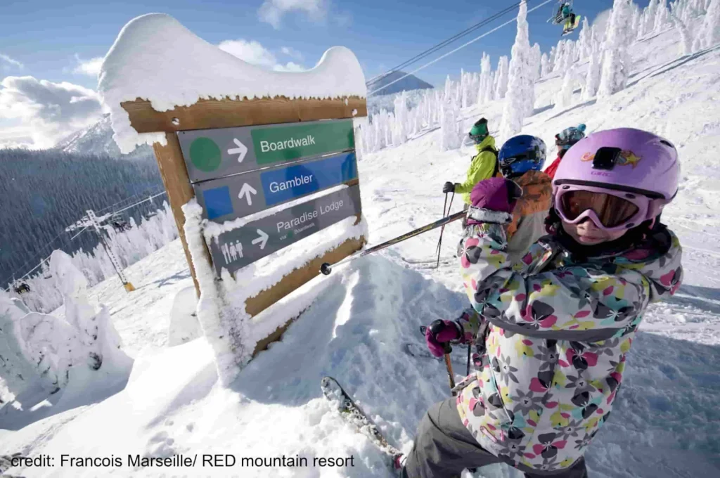 young skiers check out a sign atop Red Mountain Ski Resort