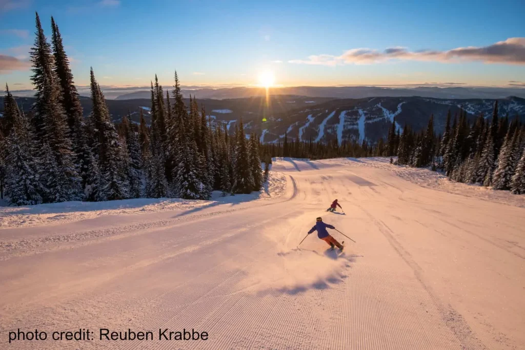 skiers descending Sun Peaks resort at sunset