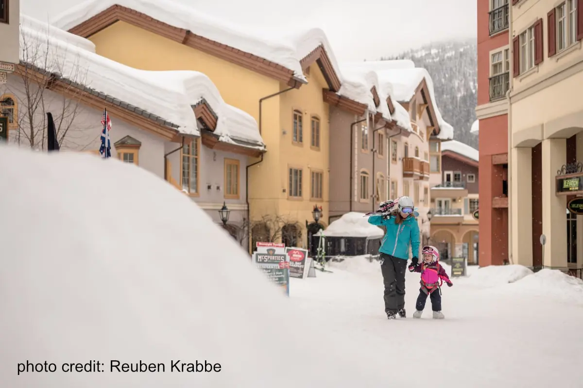 mom and daughter walking through a snowy Sun Peaks village