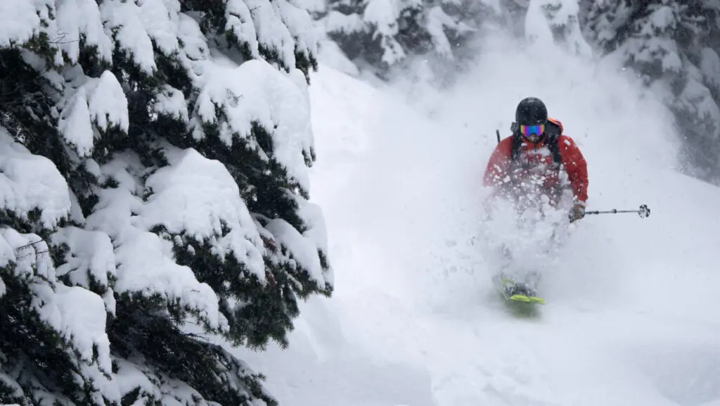 skier bursting through powder at White Grizzly lodge