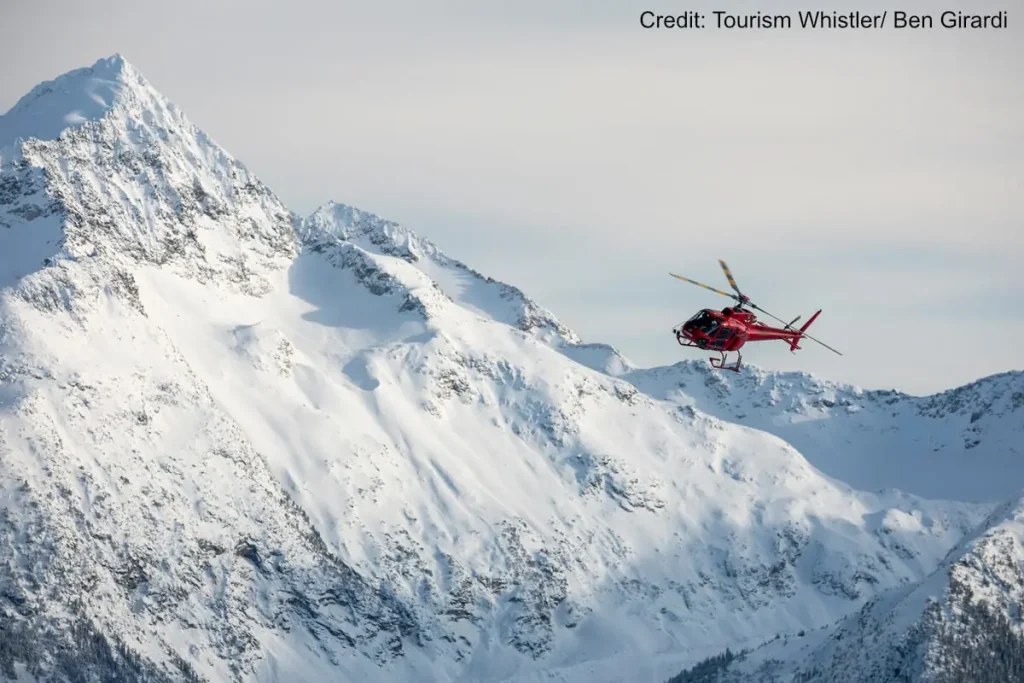 helicopter soaring over peaks near Whistler